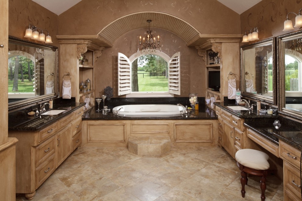 Inspiration for a large mediterranean ensuite bathroom in Houston with recessed-panel cabinets, beige cabinets, a built-in bath, brown walls, travertine flooring, a submerged sink, granite worktops and beige floors.