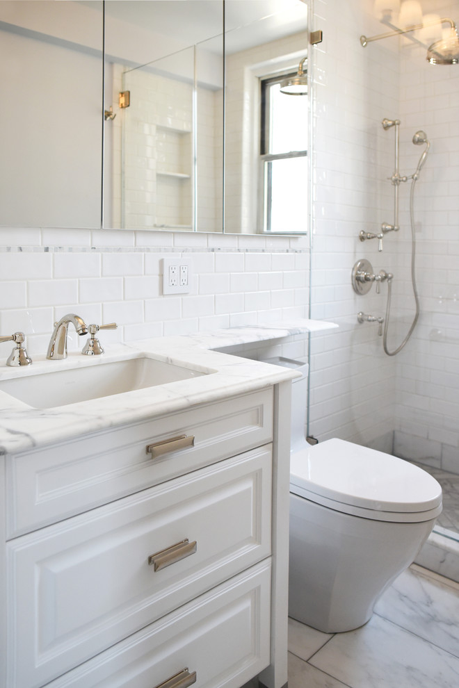 Klassisk inredning av ett litet en-suite badrum, med luckor med upphöjd panel, vita skåp, en dusch i en alkov, en toalettstol med hel cisternkåpa, vit kakel, stenkakel, vita väggar, marmorgolv, ett nedsänkt handfat och bänkskiva i kvartsit
