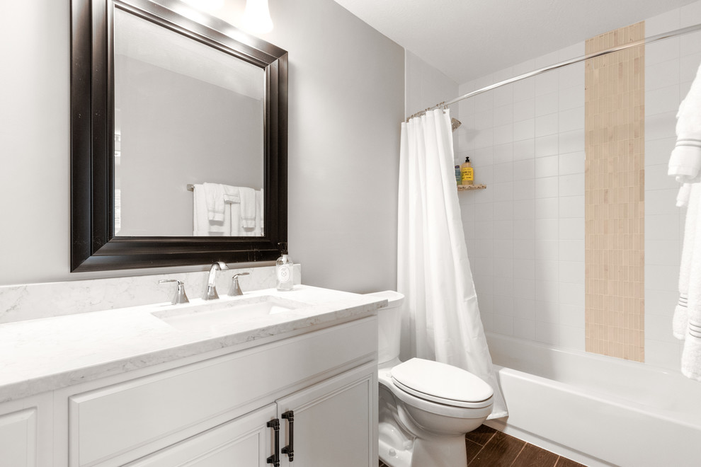 Amerikansk inredning av ett mellanstort vit vitt badrum, med släta luckor, vita skåp, ett badkar i en alkov, en dusch/badkar-kombination, en toalettstol med separat cisternkåpa, beige kakel, vit kakel, tunnelbanekakel, bruna väggar, klinkergolv i porslin, ett undermonterad handfat, bänkskiva i kvartsit, brunt golv och dusch med duschdraperi