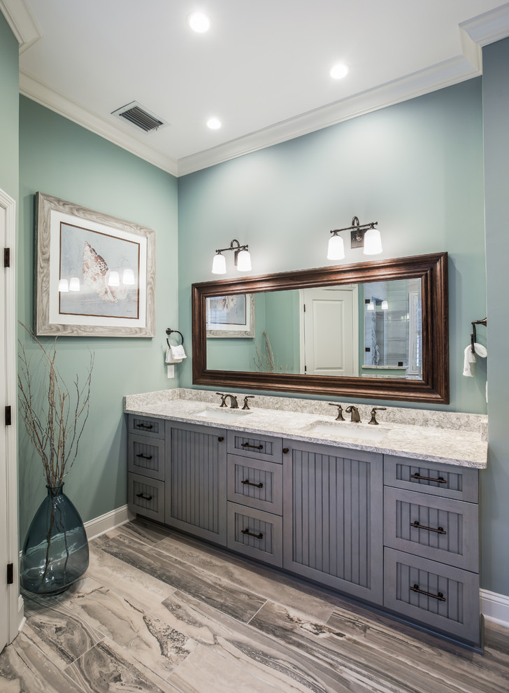 Example of a beach style green tile and porcelain tile porcelain tile and blue floor bathroom design in Jacksonville with recessed-panel cabinets, blue cabinets, a two-piece toilet, blue walls, an undermount sink, quartz countertops and multicolored countertops