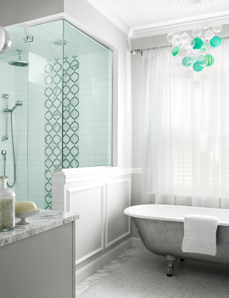 Cette image montre une salle de bain traditionnelle avec des portes de placard grises, une baignoire sur pieds, une douche d'angle, un carrelage blanc et un mur gris.