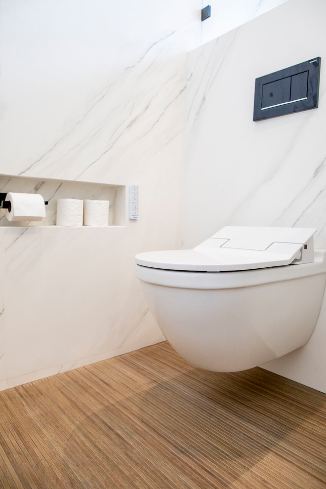 Exemple d'une grande salle de bain principale moderne en bois brun avec un placard à porte plane, un bain japonais, une douche à l'italienne, un bidet, un carrelage blanc, des carreaux de porcelaine, un mur blanc, un sol en carrelage de porcelaine, une vasque, un plan de toilette en quartz modifié, un sol noir, une cabine de douche à porte battante et un plan de toilette blanc.