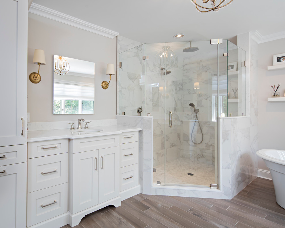 Bild på ett stort vintage vit vitt en-suite badrum, med skåp i shakerstil, vita skåp, ett fristående badkar, en hörndusch, grå kakel, marmorkakel, grå väggar, klinkergolv i porslin, ett undermonterad handfat, marmorbänkskiva, brunt golv och dusch med gångjärnsdörr