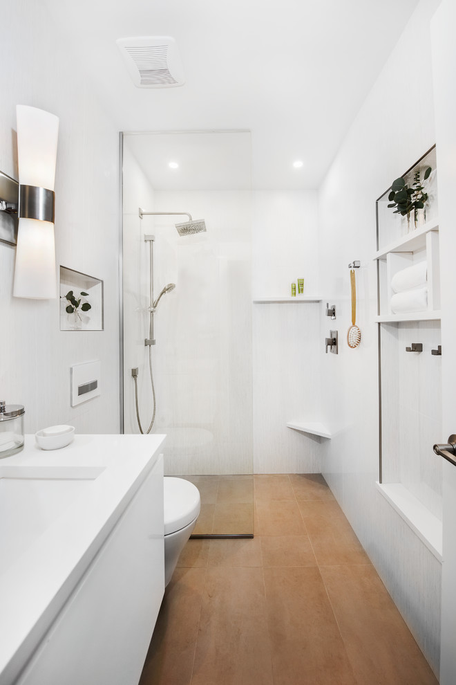 Bild på ett litet funkis vit vitt badrum med dusch, med vita väggar, ett undermonterad handfat, brunt golv, med dusch som är öppen, vita skåp, en öppen dusch, en vägghängd toalettstol, vit kakel, keramikplattor, klinkergolv i keramik, bänkskiva i kvartsit och släta luckor