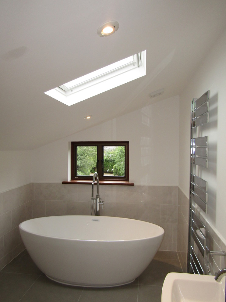 Cette photo montre une salle de bain tendance pour enfant avec une baignoire indépendante, un combiné douche/baignoire, un carrelage gris, des carreaux de céramique, un sol en carrelage de céramique et un sol gris.