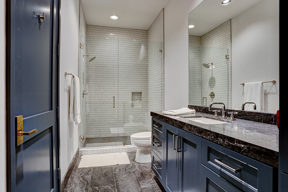 Inspiration for a traditional shower room bathroom in Houston with shaker cabinets, blue cabinets, a corner shower, white tiles, mosaic tiles, white walls, a submerged sink, black floors and a hinged door.
