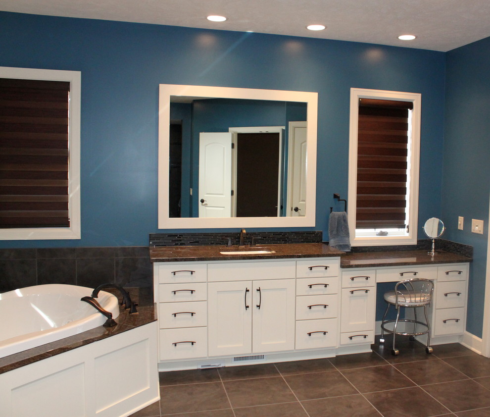 Immagine di una grande stanza da bagno padronale tradizionale con lavabo sottopiano, ante in stile shaker, ante bianche, top in superficie solida, vasca da incasso, piastrelle nere, piastrelle in ceramica, pareti blu e pavimento con piastrelle in ceramica