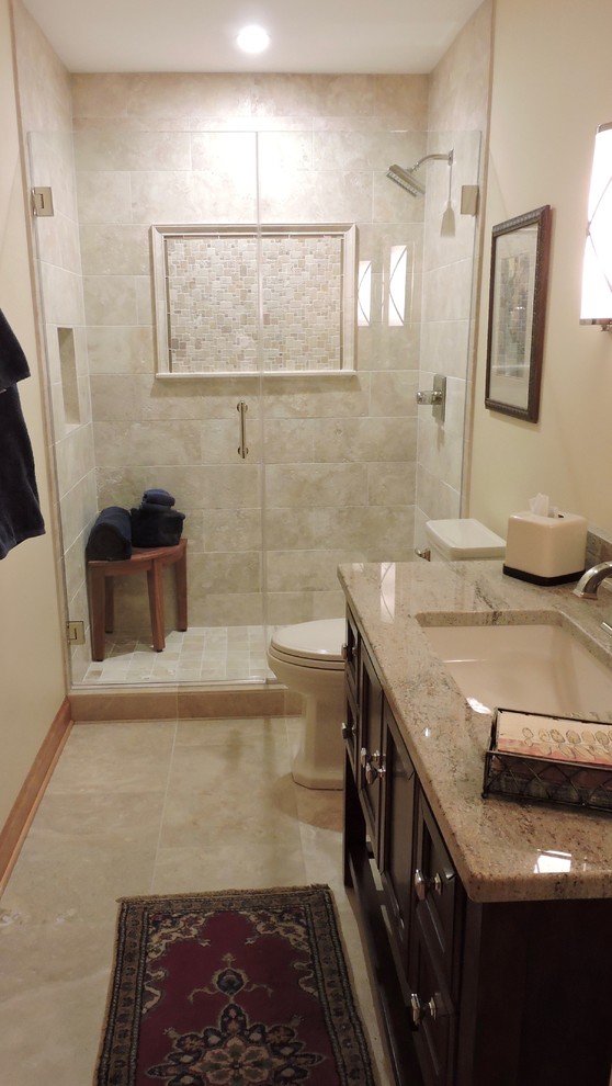 Alcove shower - mid-sized transitional master beige tile and stone tile travertine floor and beige floor alcove shower idea in Milwaukee with furniture-like cabinets, dark wood cabinets, a two-piece toilet, beige walls, an undermount sink, granite countertops and a hinged shower door