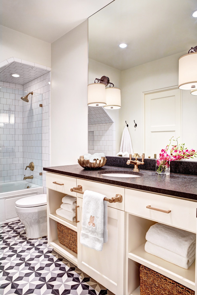 Klassisk inredning av ett mellanstort badrum, med luckor med infälld panel, vita skåp, bänkskiva i täljsten, ett badkar i en alkov, blå kakel, keramikplattor, vita väggar, klinkergolv i keramik och ett undermonterad handfat