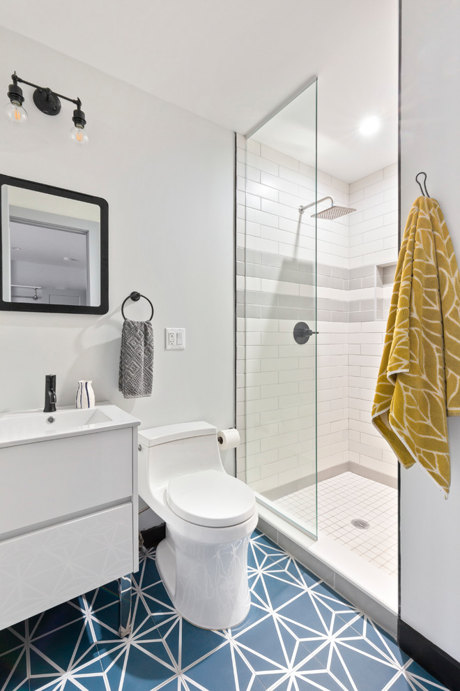 ニューヨークにある中くらいなコンテンポラリースタイルのおしゃれなバスルーム (浴槽なし) (アルコーブ型シャワー、一体型トイレ	、グレーのタイル、白いタイル、グレーの壁、セメントタイルの床、青い床、オープンシャワー、フラットパネル扉のキャビネット、白いキャビネット、サブウェイタイル、コンソール型シンク、白い洗面カウンター) の写真