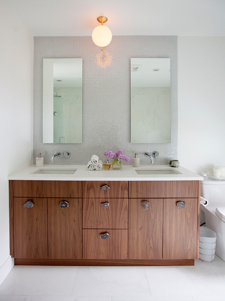 Réalisation d'une salle de bain tradition en bois brun avec un placard à porte plane, un carrelage gris, un mur blanc et un lavabo encastré.