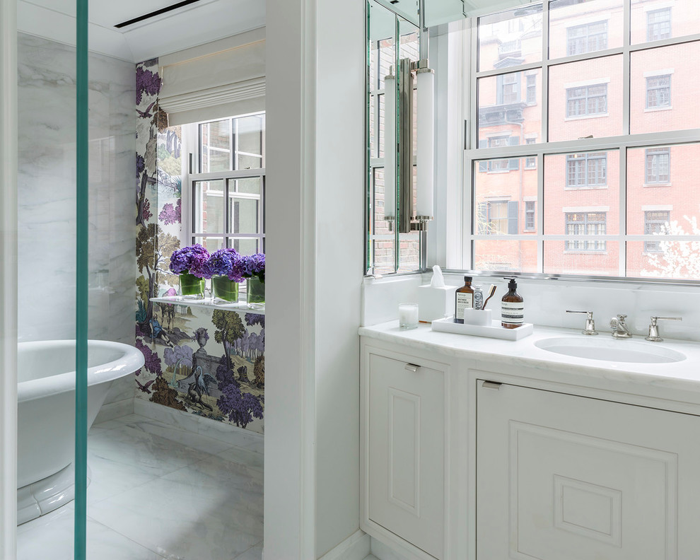 На фото: ванная комната в стиле неоклассика (современная классика) с врезной раковиной, фасадами с декоративным кантом, белыми фасадами, отдельно стоящей ванной, белой плиткой, каменной плиткой, белыми стенами и мраморным полом