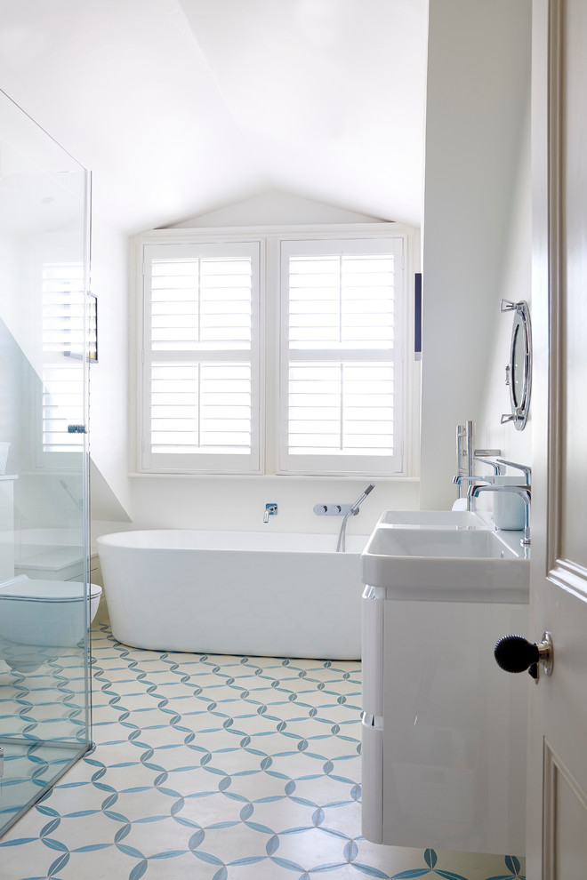 На фото: ванная комната в стиле неоклассика (современная классика) с раковиной с несколькими смесителями, отдельно стоящей ванной, душем в нише, раздельным унитазом, разноцветной плиткой, белыми стенами и полом из керамической плитки с