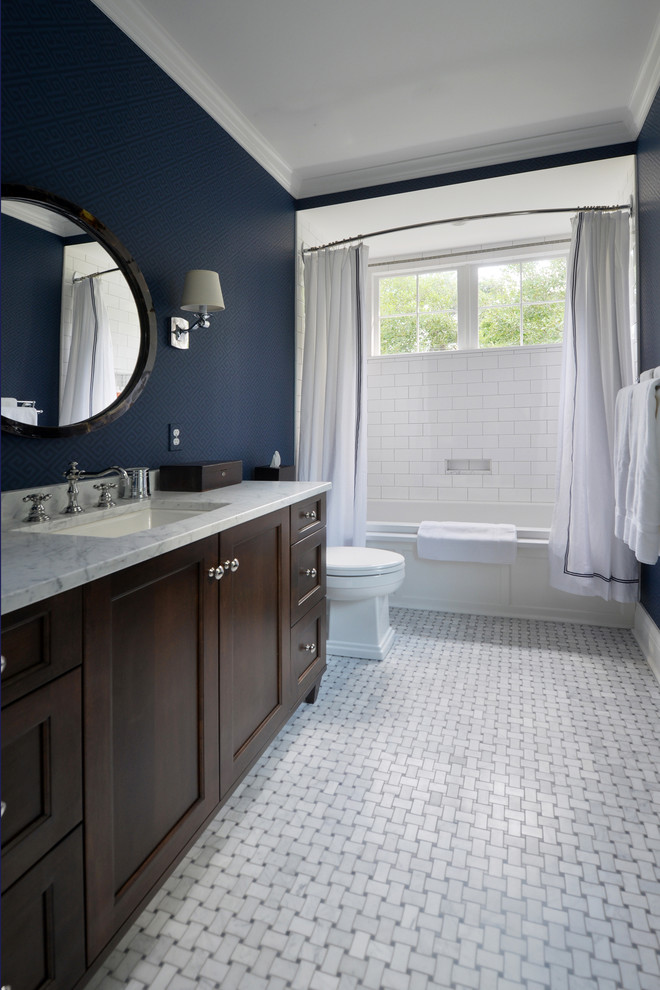 На фото: ванная комната среднего размера в стиле неоклассика (современная классика) с темными деревянными фасадами, душем над ванной, плиткой кабанчик, полом из мозаичной плитки, врезной раковиной, мраморной столешницей, фасадами в стиле шейкер, раздельным унитазом, синими стенами, ванной в нише, белой плиткой и шторкой для ванной с