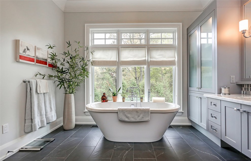 Diseño de cuarto de baño clásico renovado con armarios estilo shaker, puertas de armario grises, bañera exenta y paredes grises