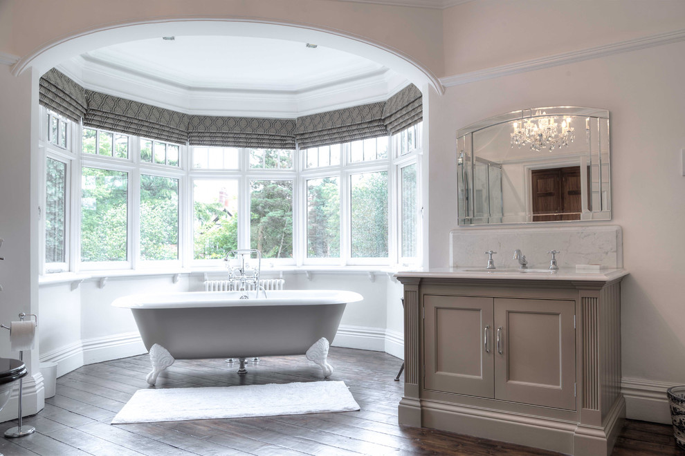 Photo of a traditional bathroom in Cheshire with recessed-panel cabinets, beige cabinets, a claw-foot bath and dark hardwood flooring.