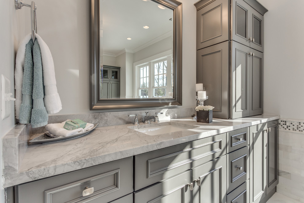 Diseño de cuarto de baño clásico renovado con puertas de armario grises, bañera exenta, lavabo bajoencimera y encimera de mármol