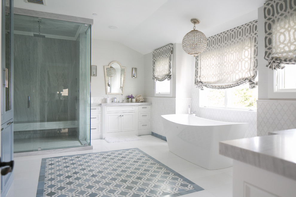 This is an example of a classic ensuite bathroom in Orange County with recessed-panel cabinets, white cabinets, a freestanding bath, a corner shower, white tiles and grey walls.