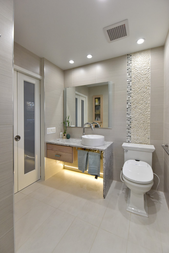 Traditional bathroom in DC Metro with open cabinets, beige tiles, black and white tiles, pebble tiles, beige walls, a vessel sink and grey floors.