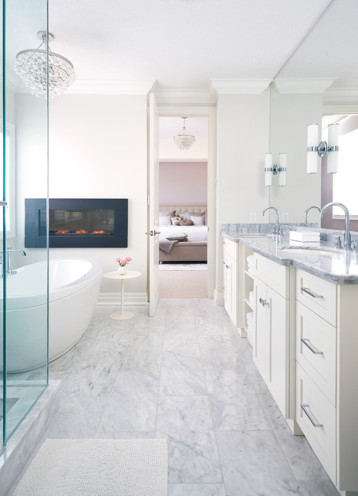 Klassisk inredning av ett mycket stort en-suite badrum, med ett undermonterad handfat, skåp i shakerstil, vita skåp, marmorbänkskiva, ett fristående badkar, vit kakel, stenkakel, vita väggar och marmorgolv