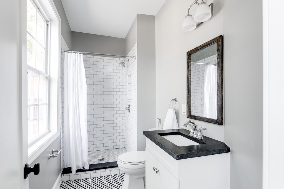 Bild på ett vintage svart svart badrum med dusch, med vita skåp, en dusch i en alkov, vit kakel, tunnelbanekakel, grå väggar, ett undermonterad handfat, flerfärgat golv och dusch med duschdraperi