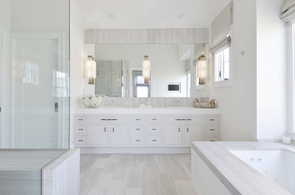 Immagine di una stanza da bagno chic con ante lisce, ante bianche e vasca sottopiano
