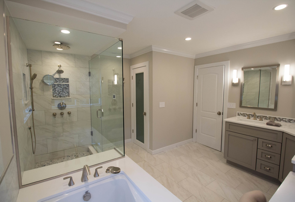 Corner shower - large transitional master white tile and porcelain tile porcelain tile corner shower idea in Newark with shaker cabinets, gray cabinets, an undermount tub, a one-piece toilet, beige walls, an undermount sink and quartz countertops