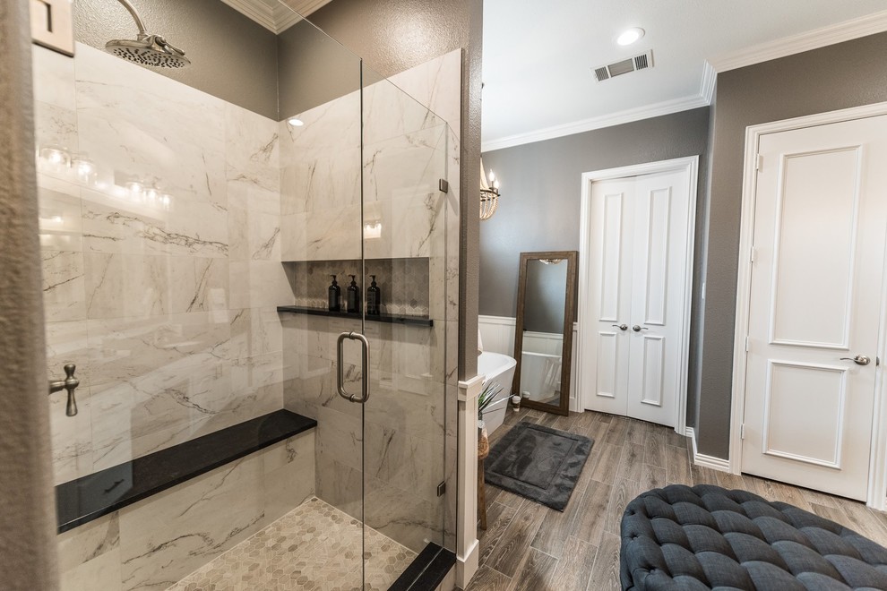 Photo of a large traditional ensuite bathroom in Dallas with white cabinets, a freestanding bath, an alcove shower, multi-coloured tiles, porcelain tiles, grey walls, porcelain flooring, a submerged sink, granite worktops, brown floors, a hinged door and black worktops.