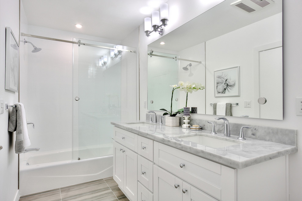 Mid-sized transitional white tile and porcelain tile porcelain tile bathroom photo in Los Angeles with an undermount sink, shaker cabinets, white cabinets, marble countertops, a one-piece toilet and white walls