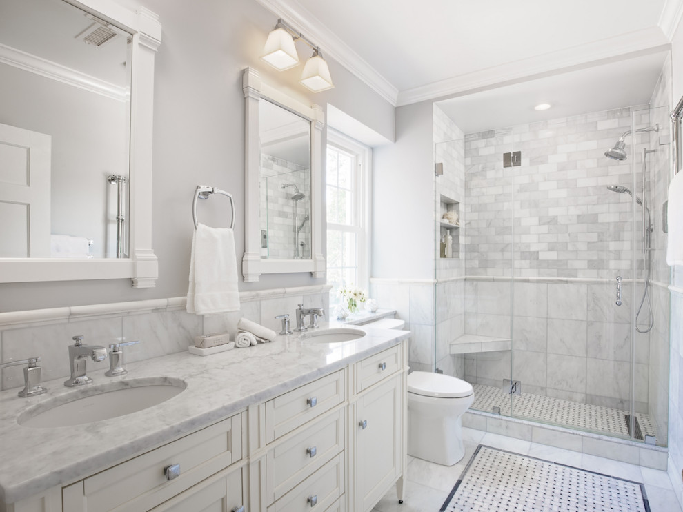 Klassisk inredning av ett mellanstort grå grått en-suite badrum, med vita skåp, en dusch i en alkov, en toalettstol med separat cisternkåpa, grå kakel, marmorkakel, grå väggar, marmorgolv, ett undermonterad handfat, marmorbänkskiva, grått golv, dusch med gångjärnsdörr och luckor med infälld panel