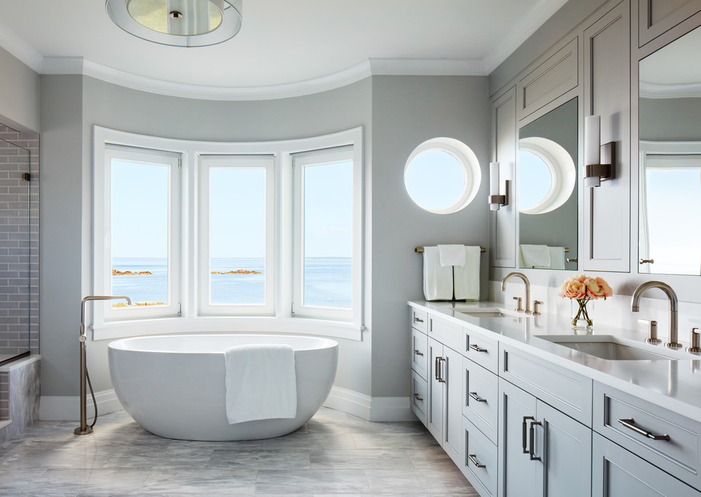 Foto di una stanza da bagno classica con ante con riquadro incassato, ante grigie, vasca freestanding, pareti grigie, lavabo sottopiano, pavimento grigio e top bianco