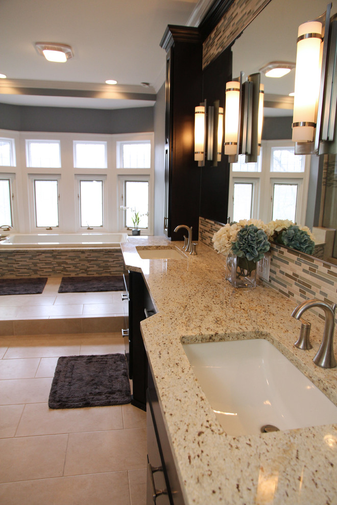 Klassisk inredning av ett mycket stort en-suite badrum, med skåp i mörkt trä, granitbänkskiva, flerfärgad kakel, grå väggar, klinkergolv i porslin, stickkakel och ett platsbyggt badkar
