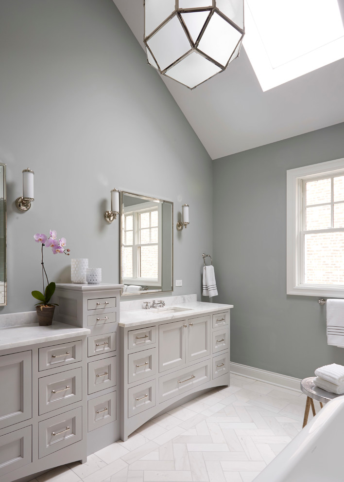Klassisk inredning av ett stort en-suite badrum, med luckor med infälld panel, grå skåp, ett fristående badkar, en dusch i en alkov, grå kakel, keramikplattor, grå väggar, marmorgolv, ett undermonterad handfat och marmorbänkskiva