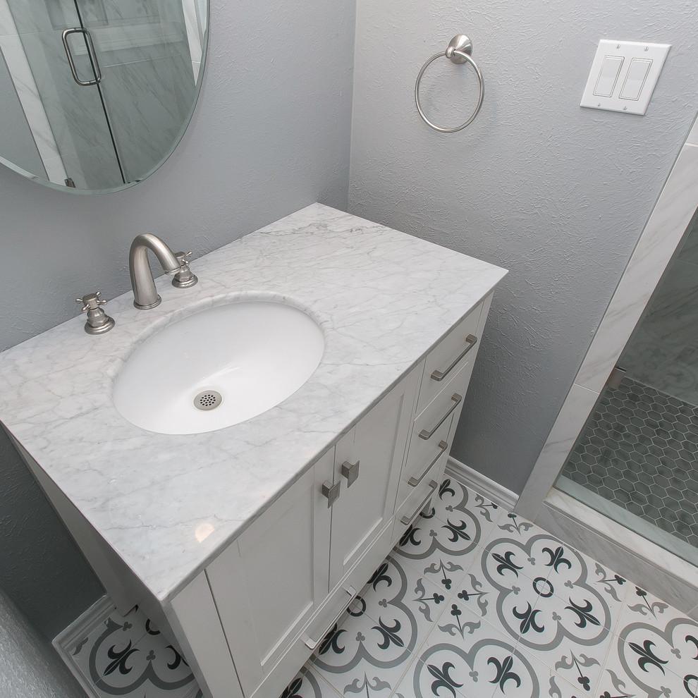 На фото: маленькая ванная комната в современном стиле с фасадами в стиле шейкер, белыми фасадами, угловым душем, унитазом-моноблоком, серой плиткой, белой плиткой, керамогранитной плиткой, серыми стенами, полом из цементной плитки, душевой кабиной, врезной раковиной, мраморной столешницей, разноцветным полом, душем с распашными дверями и серой столешницей для на участке и в саду с