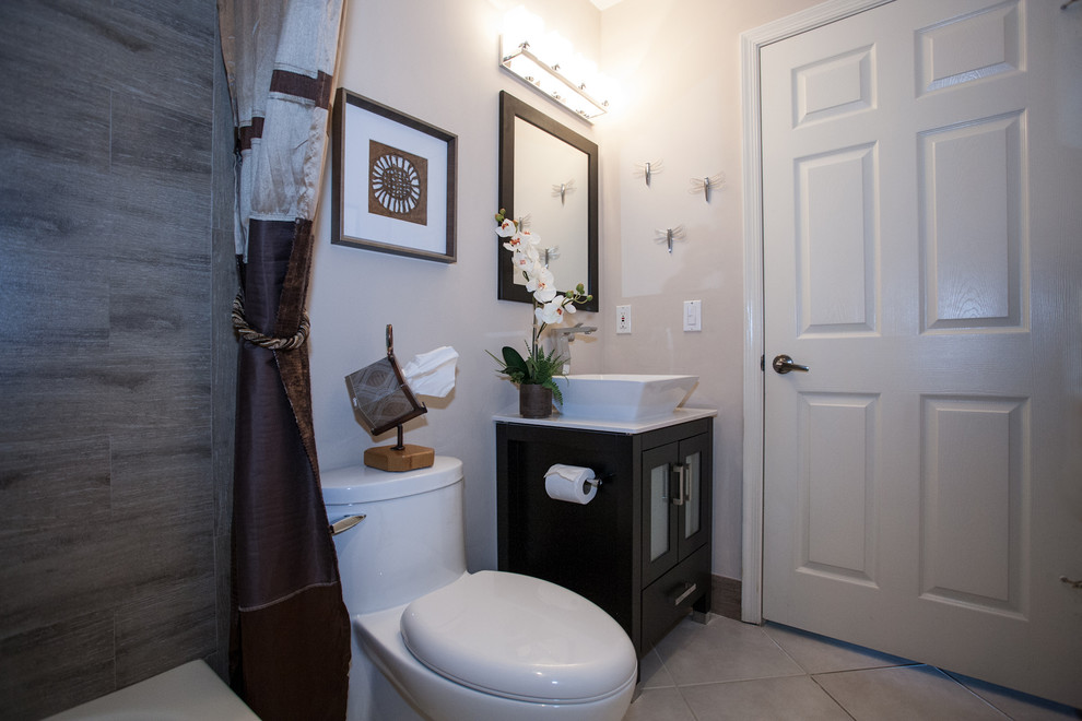 Exempel på ett klassiskt badrum, med ett fristående handfat, möbel-liknande, svarta skåp, bänkskiva i kvartsit, ett badkar i en alkov, en dusch/badkar-kombination, en toalettstol med hel cisternkåpa, flerfärgad kakel och porslinskakel