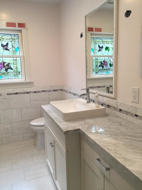 Photo of a medium sized classic ensuite half tiled bathroom in Salt Lake City with shaker cabinets, white cabinets, a two-piece toilet, white tiles, stone tiles, beige walls, marble flooring, a built-in sink and quartz worktops.