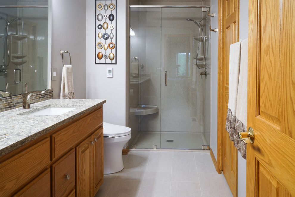 Bild på ett mellanstort vintage badrum med dusch, med luckor med upphöjd panel, skåp i mellenmörkt trä, en bidé, beige kakel, brun kakel, grå kakel, flerfärgad kakel, stickkakel, grå väggar, skiffergolv, ett undermonterad handfat, granitbänkskiva och en dusch i en alkov