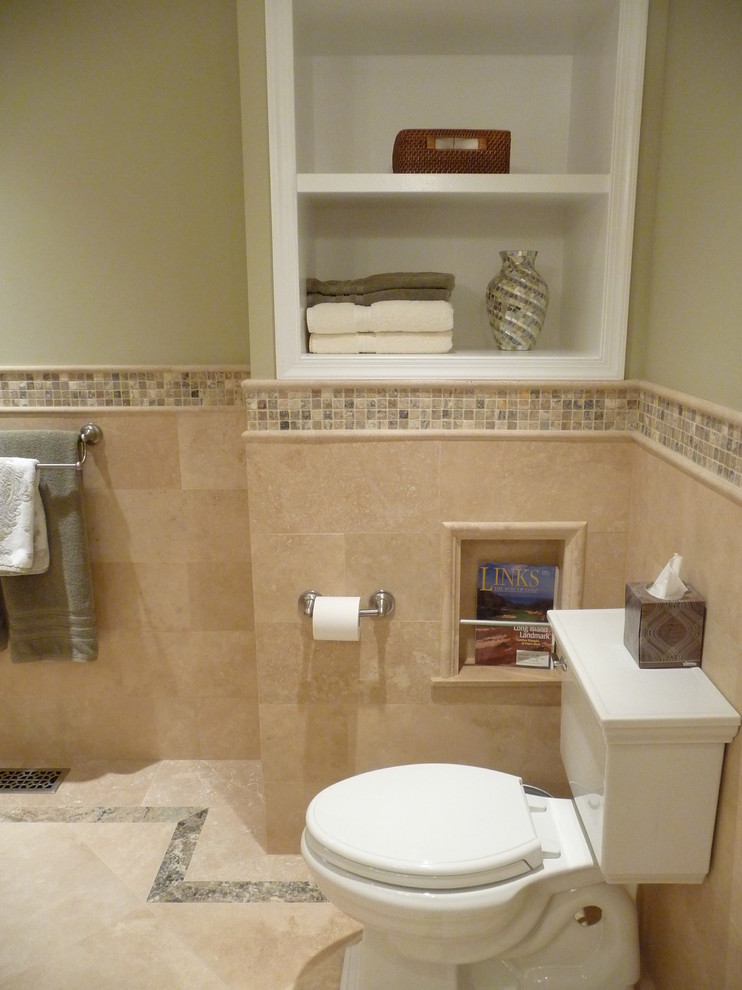 Klassisk inredning av ett badrum, med en toalettstol med separat cisternkåpa, beige kakel och travertinkakel