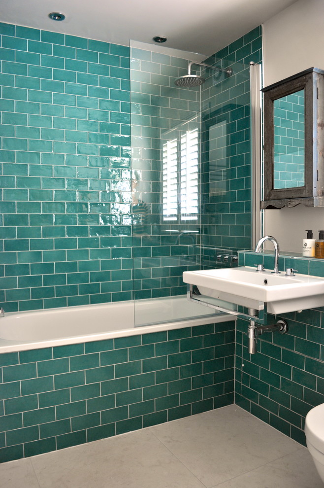 Modelo de cuarto de baño tradicional renovado con lavabo suspendido, bañera empotrada y baldosas y/o azulejos azules