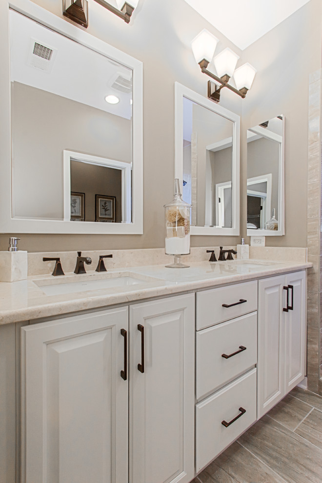 Imagen de cuarto de baño tradicional renovado con armarios con paneles con relieve, puertas de armario blancas, baldosas y/o azulejos marrones, paredes grises y lavabo bajoencimera
