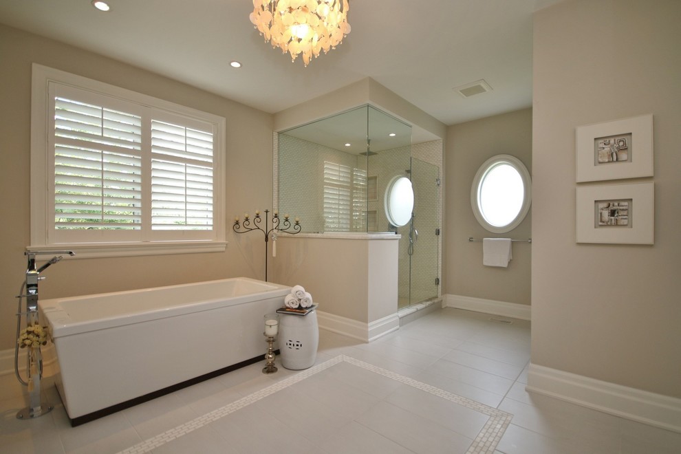 Idées déco pour une salle de bain principale classique de taille moyenne avec des portes de placard blanches, un plan de toilette en marbre, une baignoire indépendante, un carrelage gris et un mur beige.