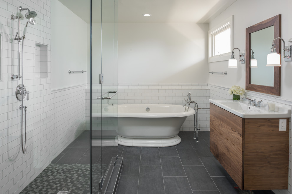 Klassisches Badezimmer mit flächenbündigen Schrankfronten, hellbraunen Holzschränken, freistehender Badewanne, weißen Fliesen, Metrofliesen, weißer Wandfarbe, Waschtischkonsole und Falttür-Duschabtrennung in San Diego