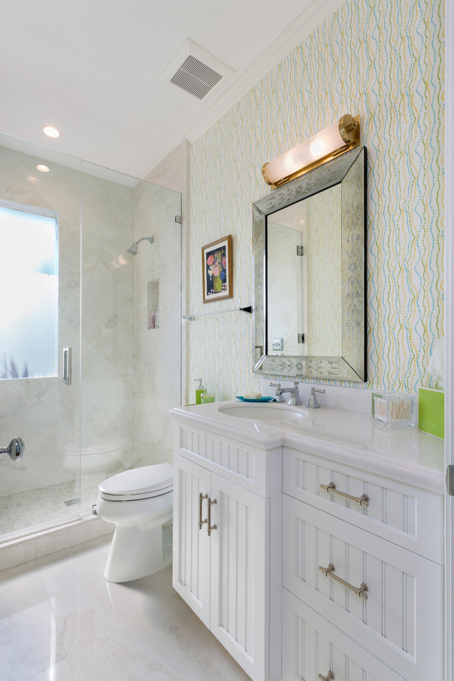 Example of a mid-sized transitional master beige tile and porcelain tile porcelain tile and beige floor alcove shower design in Miami with shaker cabinets, white cabinets, a one-piece toilet, multicolored walls, an undermount sink, marble countertops, a hinged shower door and white countertops