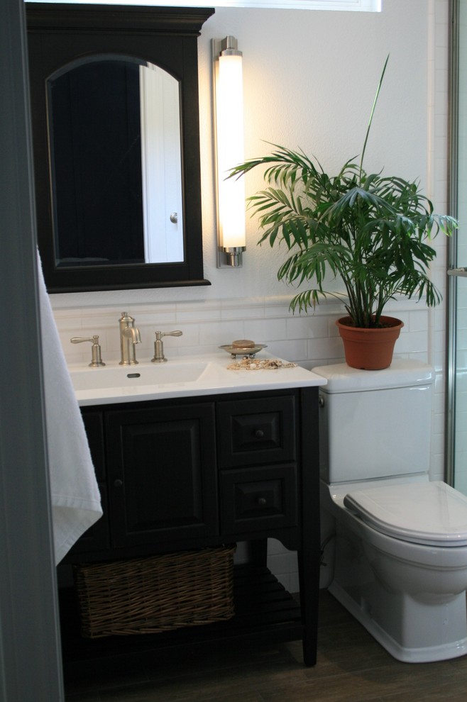 Cette photo montre une petite salle de bain chic avec un lavabo intégré, un placard en trompe-l'oeil, des portes de placard noires, WC à poser, un carrelage blanc, des carreaux de céramique, un mur blanc et un sol en carrelage de porcelaine.