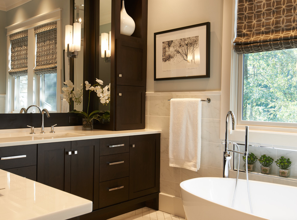 Ejemplo de cuarto de baño principal tradicional renovado de tamaño medio con lavabo bajoencimera, armarios con paneles empotrados, puertas de armario de madera en tonos medios, bañera exenta y paredes grises