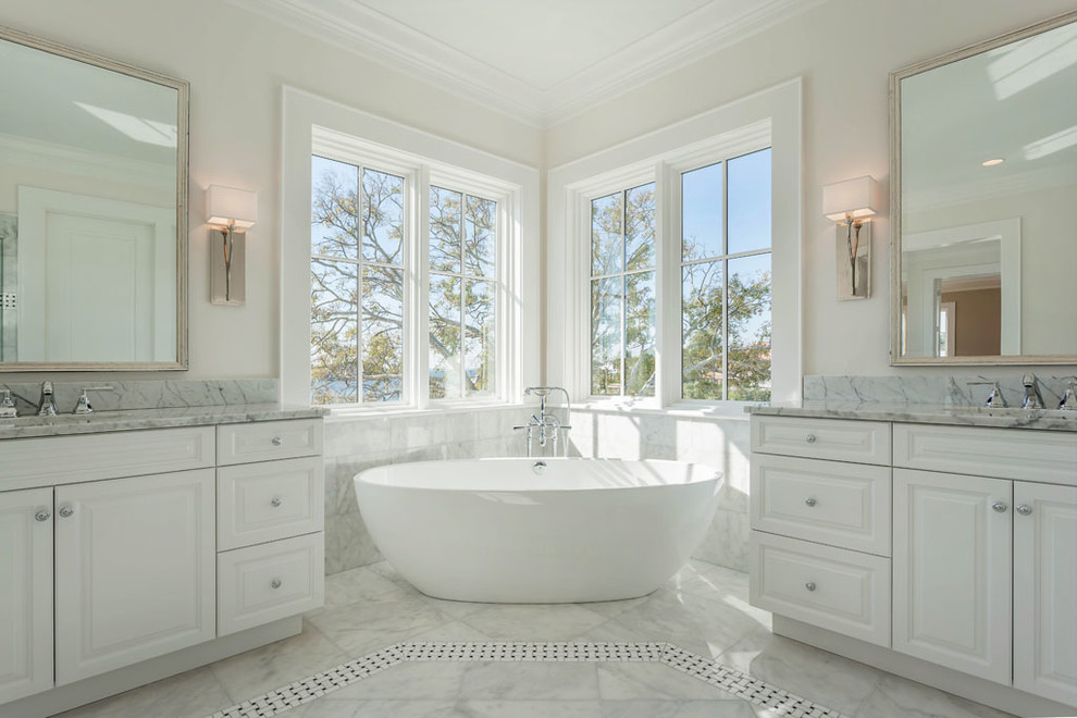 Inredning av ett klassiskt stort grå grått en-suite badrum, med luckor med upphöjd panel, vita skåp, ett fristående badkar, en hörndusch, grå kakel, vit kakel, marmorkakel, vita väggar, marmorgolv, ett undermonterad handfat, dusch med gångjärnsdörr, marmorbänkskiva och grått golv