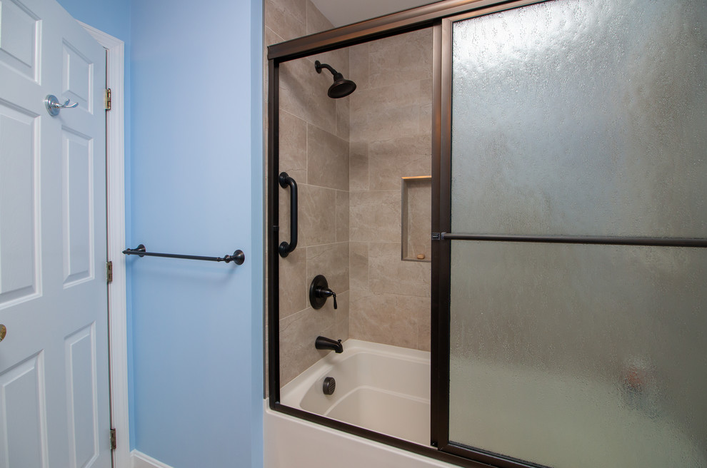 Klassisk inredning av ett mellanstort flerfärgad flerfärgat badrum med dusch, med luckor med upphöjd panel, skåp i mörkt trä, ett badkar i en alkov, en dusch/badkar-kombination, en toalettstol med separat cisternkåpa, beige kakel, porslinskakel, blå väggar, vinylgolv, ett undermonterad handfat, bänkskiva i kvarts, brunt golv och dusch med skjutdörr