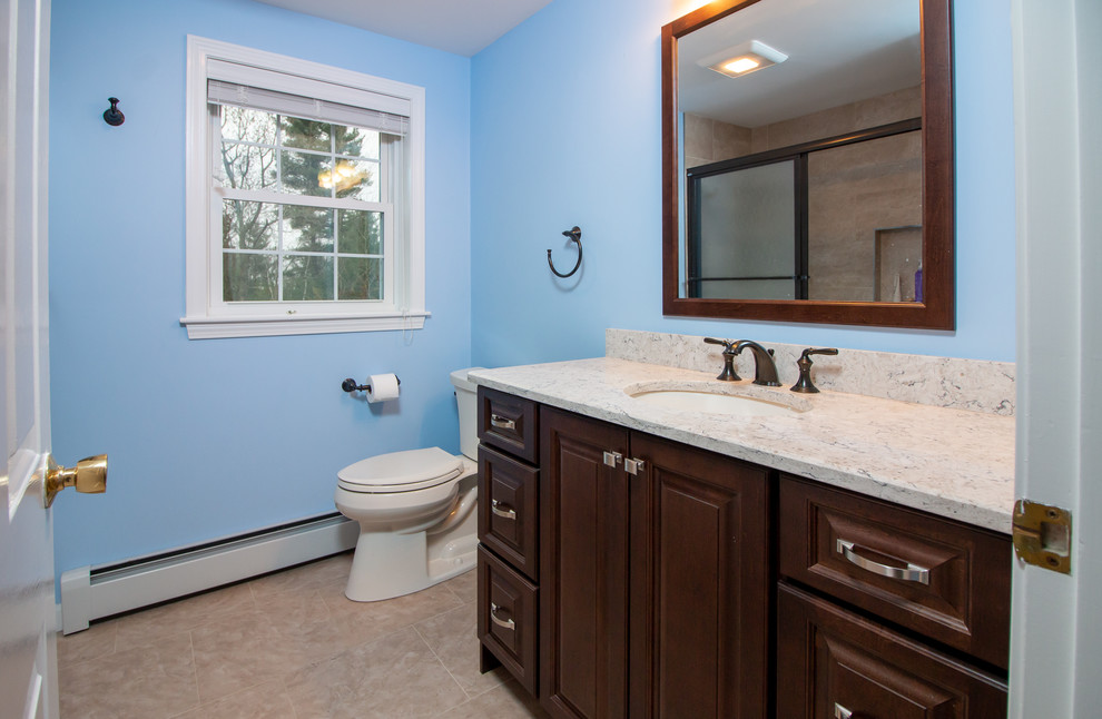 Inspiration for a mid-sized transitional 3/4 beige tile and porcelain tile vinyl floor and brown floor bathroom remodel in Boston with raised-panel cabinets, dark wood cabinets, a two-piece toilet, blue walls, an undermount sink, quartz countertops and multicolored countertops