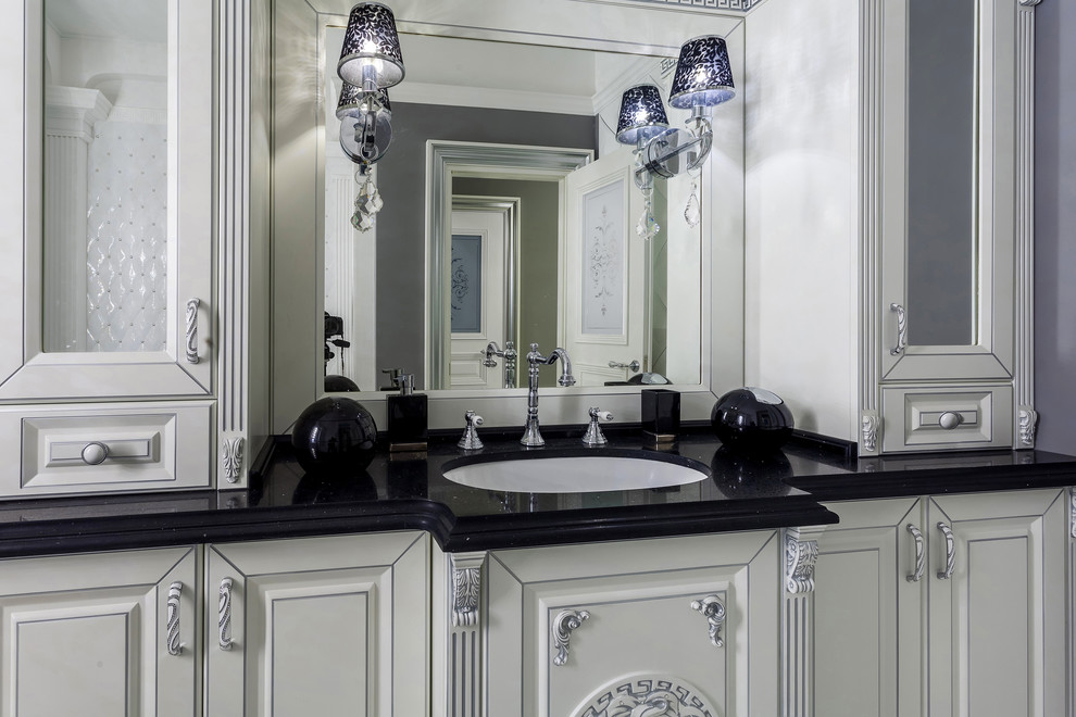 Свежая идея для дизайна: главная ванная комната среднего размера в классическом стиле с фасадами с выступающей филенкой, белыми фасадами, отдельно стоящей ванной, серой плиткой, плиткой из известняка, серыми стенами, полом из известняка, накладной раковиной, мраморной столешницей, разноцветным полом и черной столешницей - отличное фото интерьера