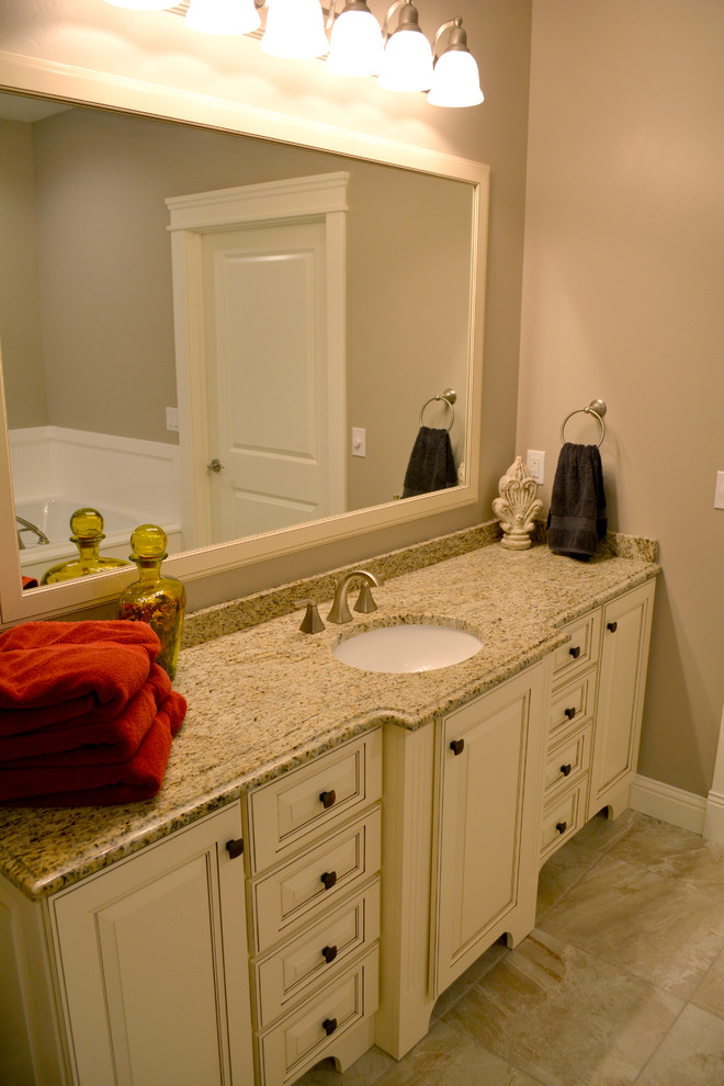 Foto på ett mellanstort vintage en-suite badrum, med ett undermonterad handfat, luckor med upphöjd panel, granitbänkskiva, beige kakel, keramikplattor, beige väggar, klinkergolv i keramik och vita skåp